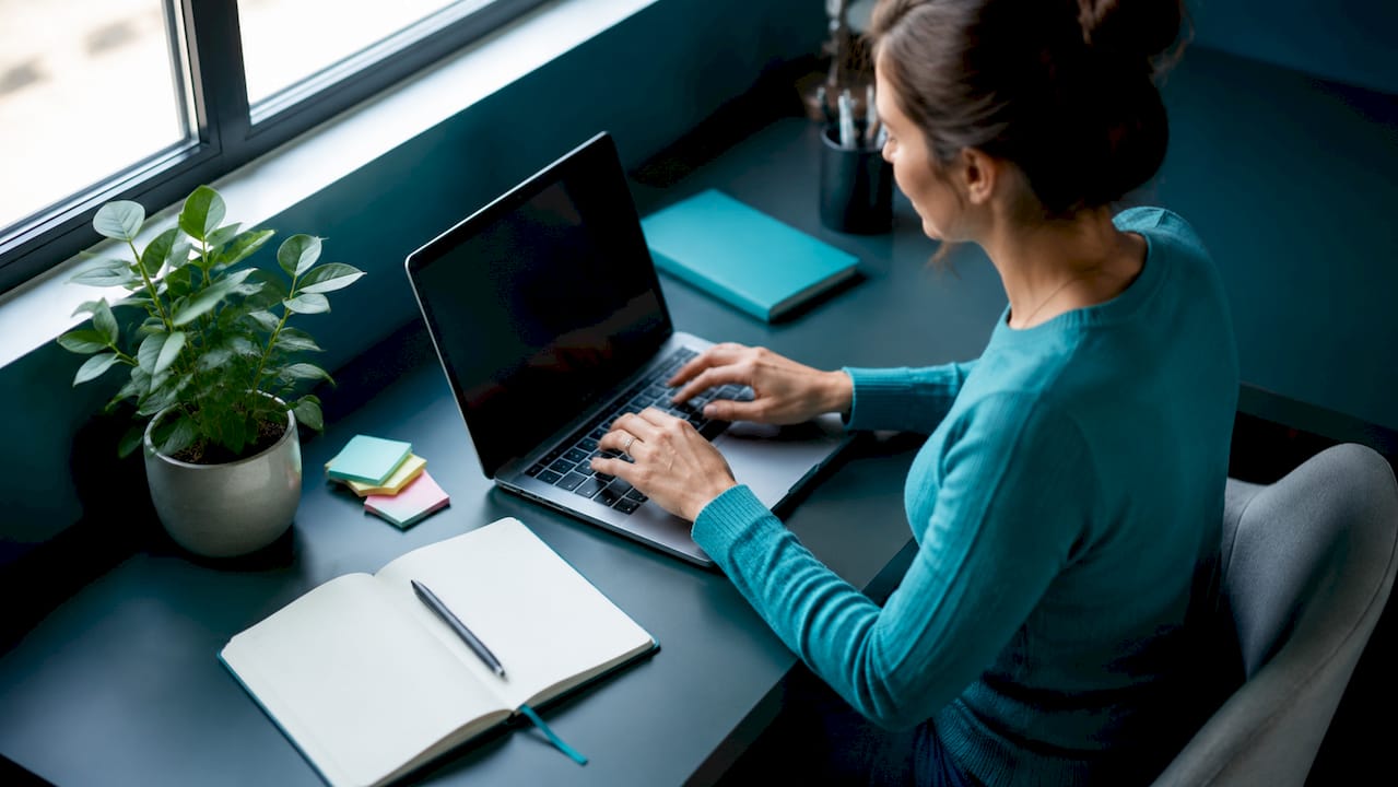 Des mains qui s’activent sur le clavier d’un ordinateur portable, posées sur un bureau contemporain.