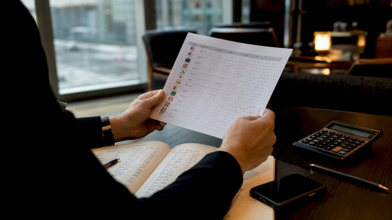 Hands holding currency spreadsheet documents