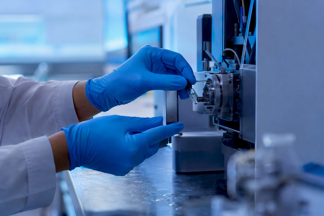 Gloved hand placing peptide vial into LC-MS injector