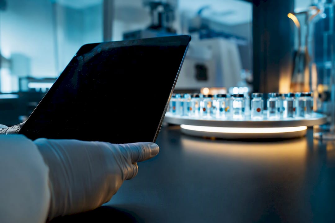 Gloved hand holding tablet near peptide samples