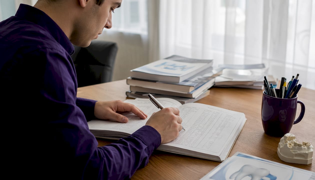 Hands marking dental income ledger