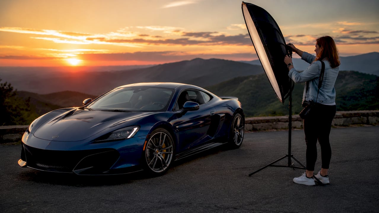 Photographer adjusting reflector during golden hour car shoot