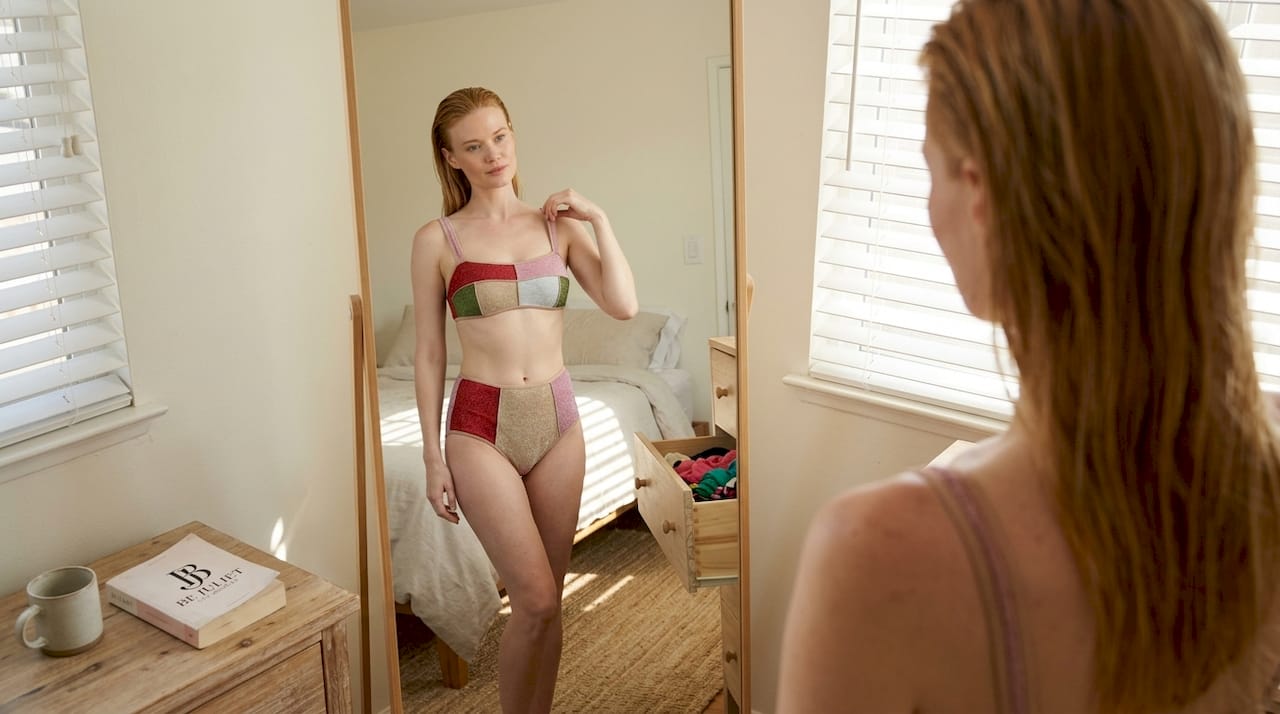 Woman trying swimsuit in bedroom mirror