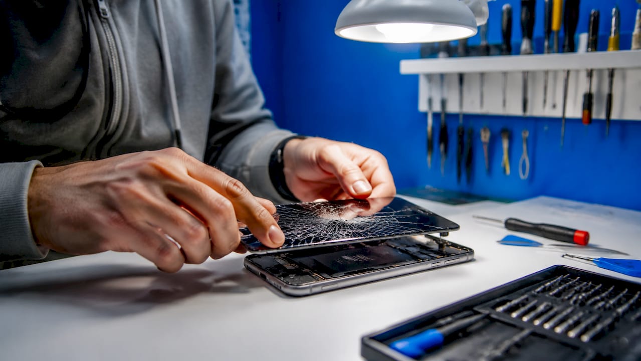 Close-up hands replacing cracked smartphone screen