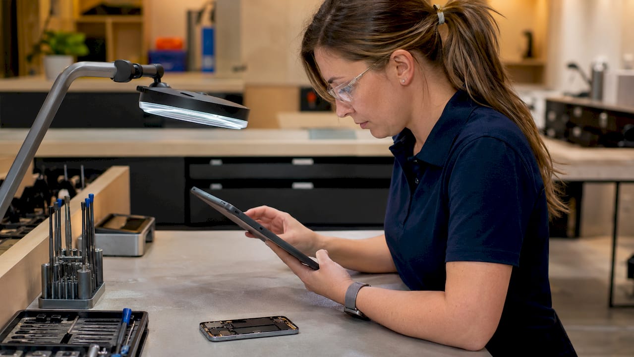 Technician using diagnostic tools on phone at workstation