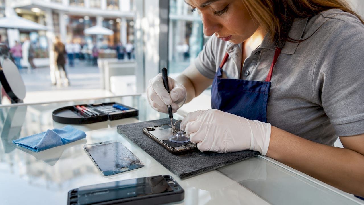 Hands replacing smartphone screen in repair kiosk