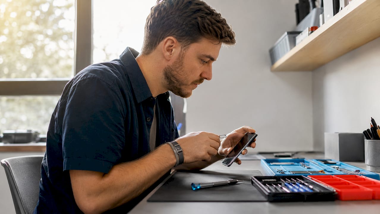 Technician removing SIM card tray from iPhone