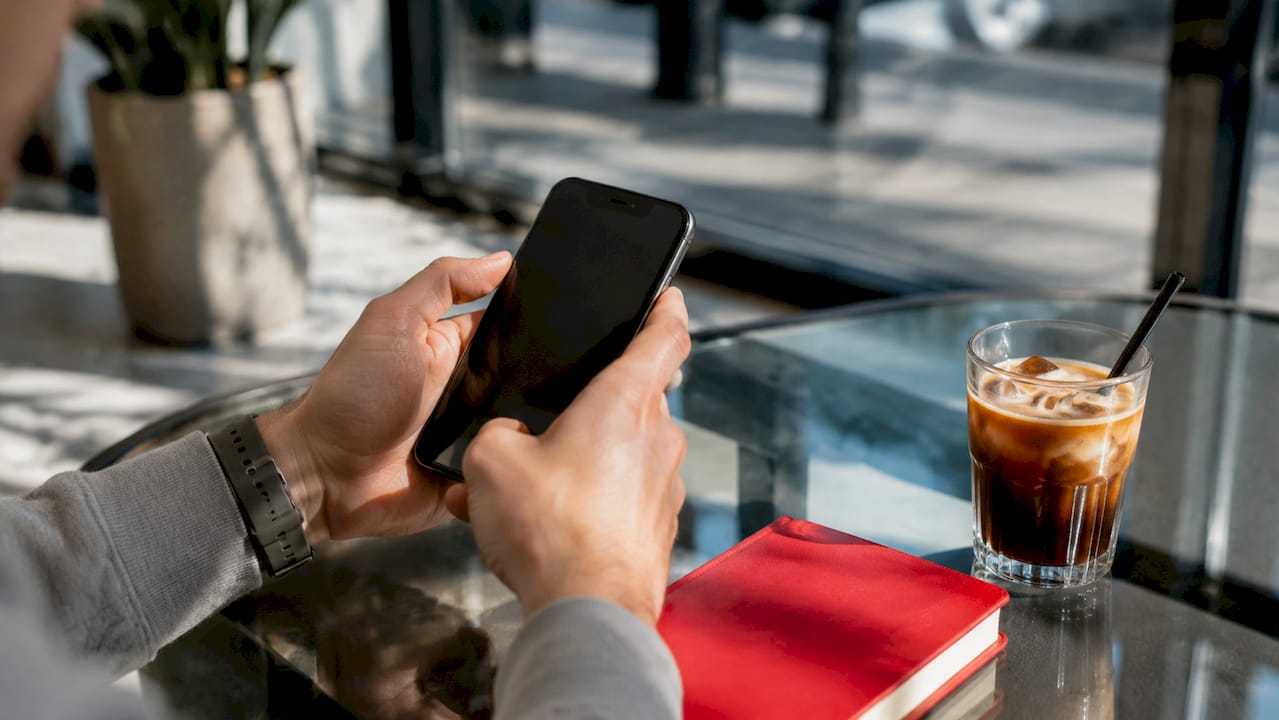 Hands force restarting an iPhone at home table