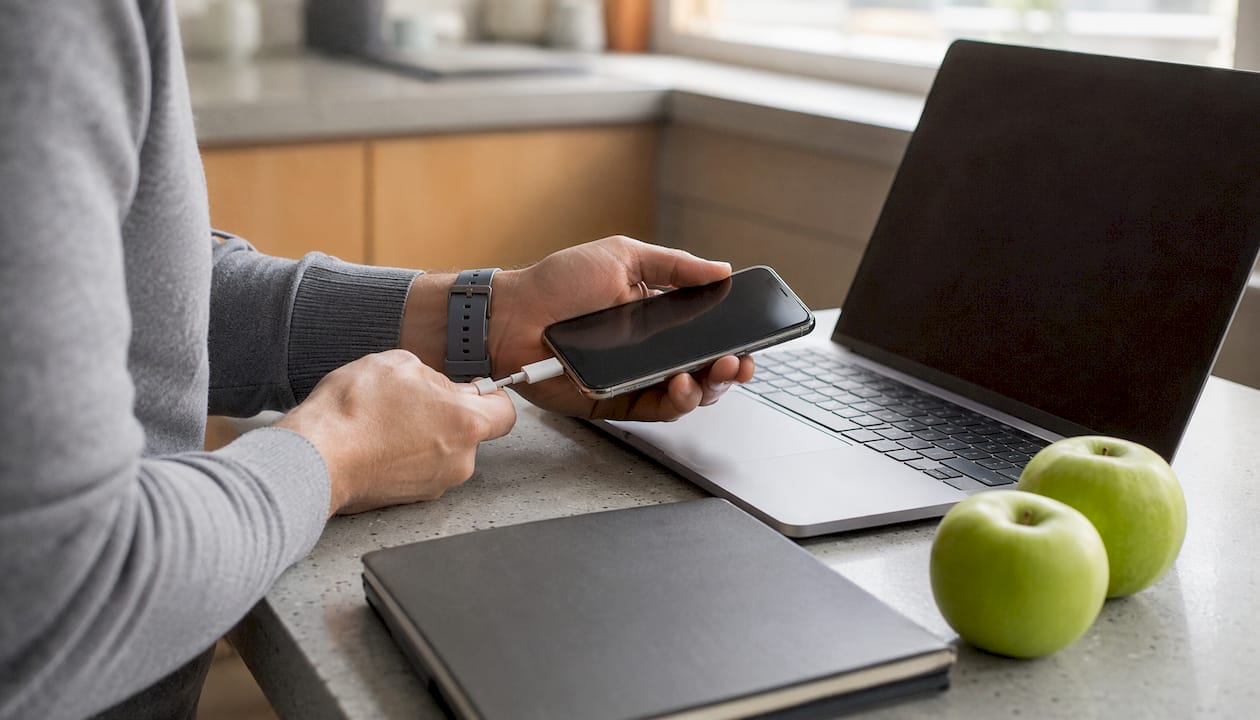 Hands connecting iPhone to MacBook for recovery
