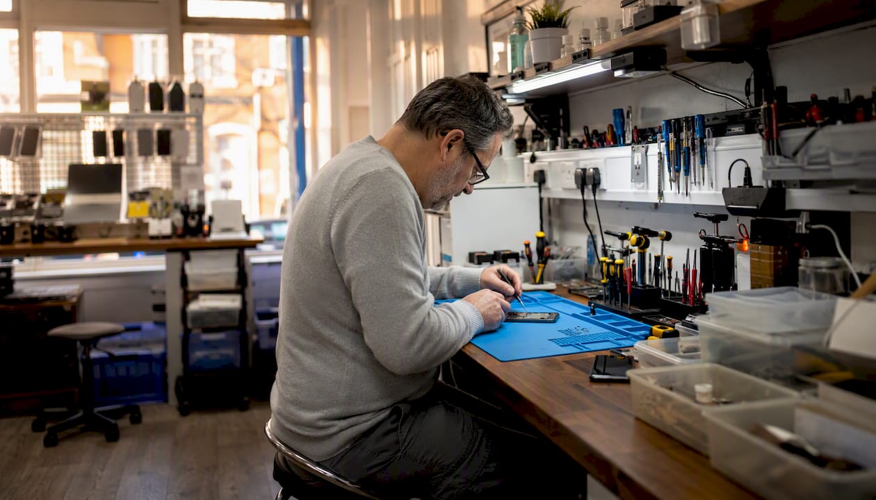 Technician repairing iPhone screen at workbench