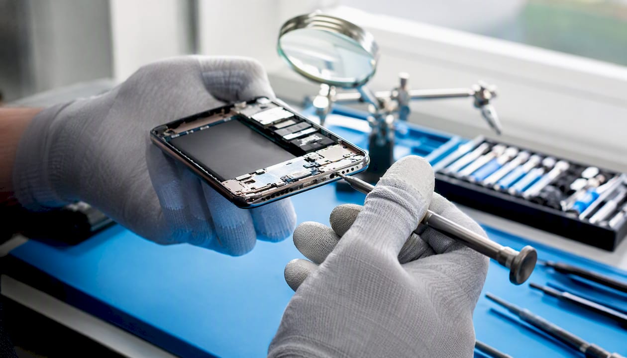 Hands repairing smartphone microphone port close-up