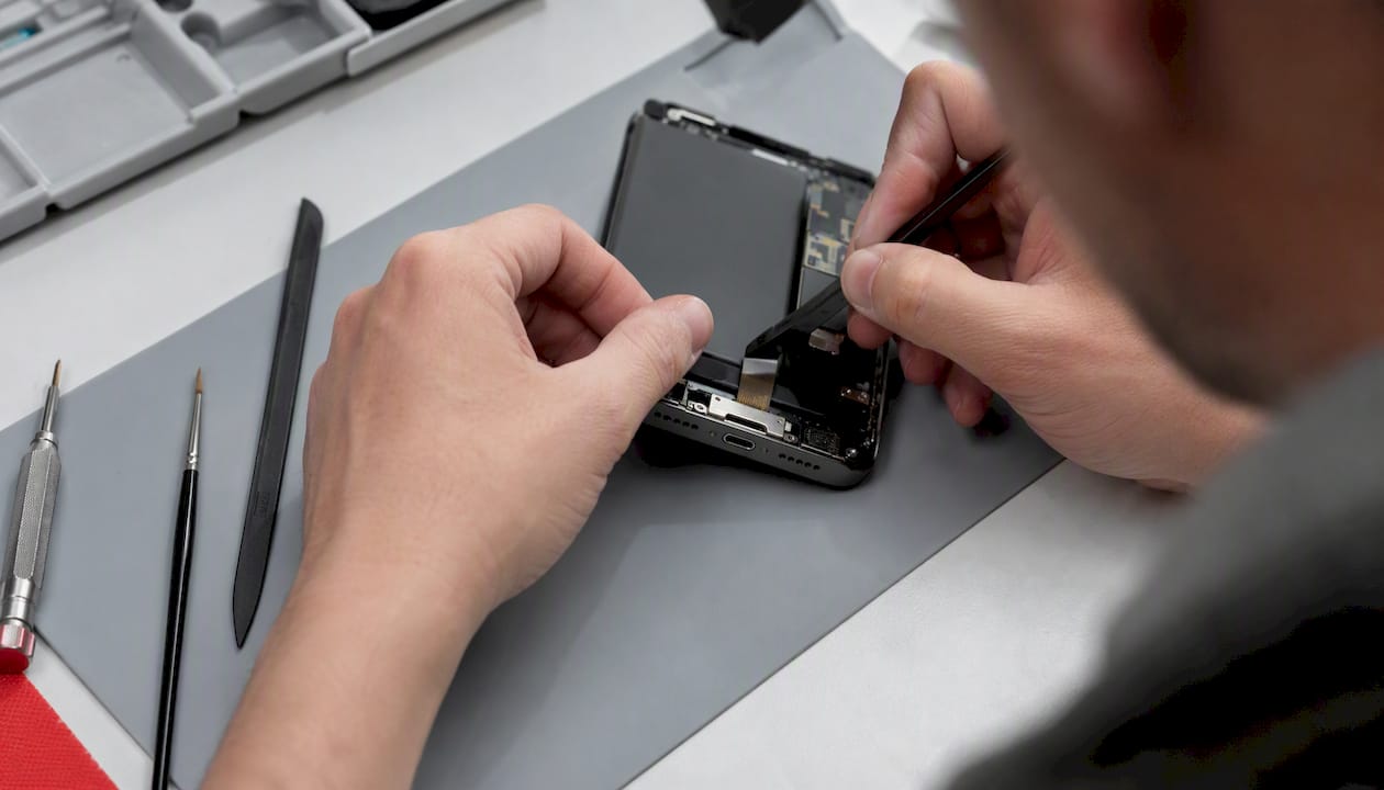 Hands inspecting smartphone battery and charging port