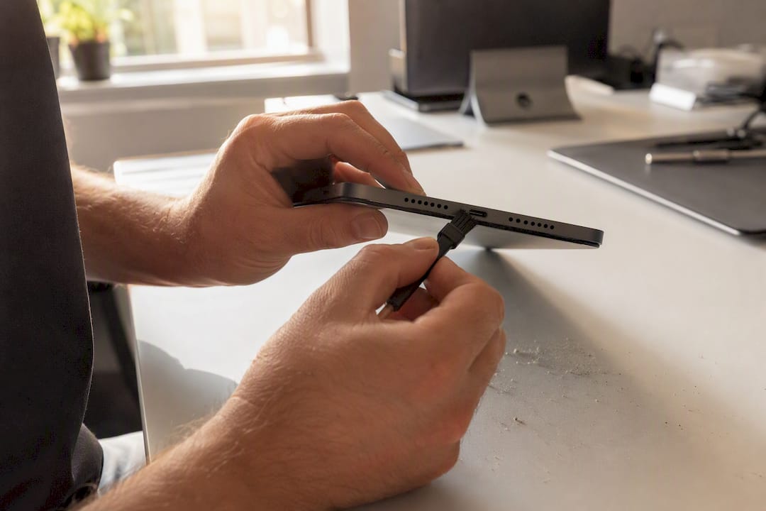 Hands brushing lint out of tablet charging port