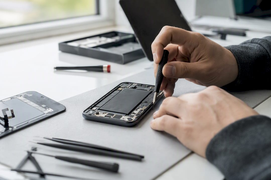 Hands removing adhesive inside iPhone