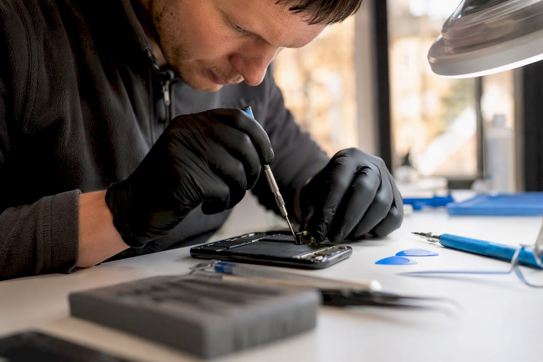 Technician removing iPhone battery at repair bench
