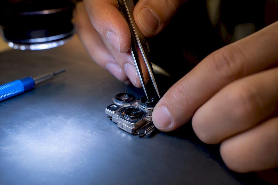 Technician aligning a smartphone camera assembly