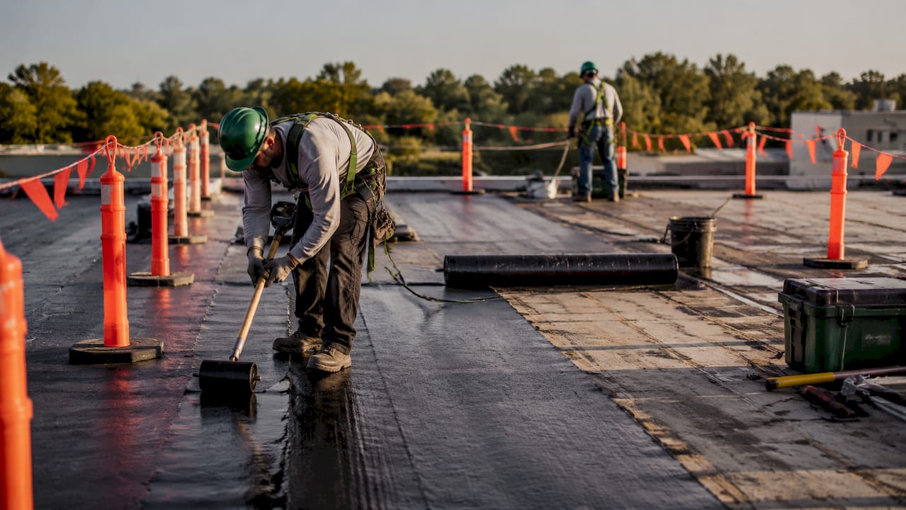 Hands installing roofing membrane in isolated repair zone