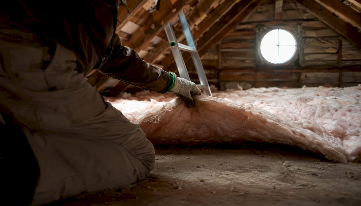 Hands checking attic insulation and moisture