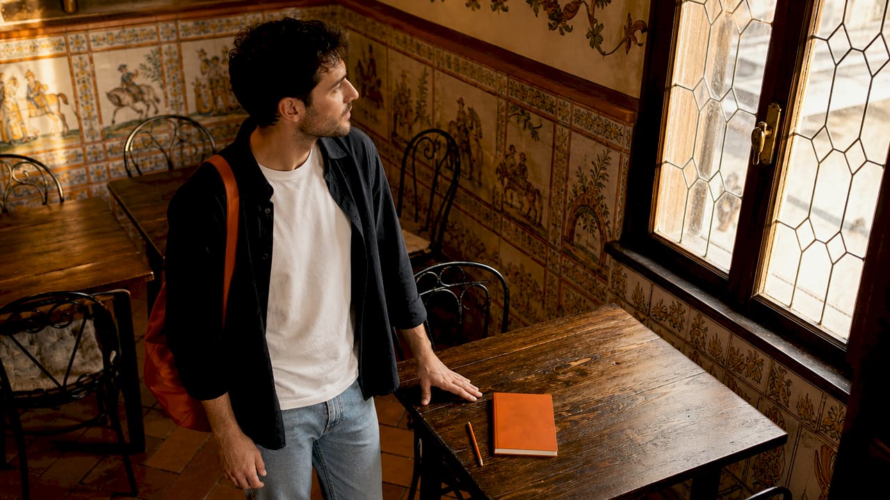 Un ragazzo sta valutando l'atmosfera della trattoria prima di decidere se prenotare.
