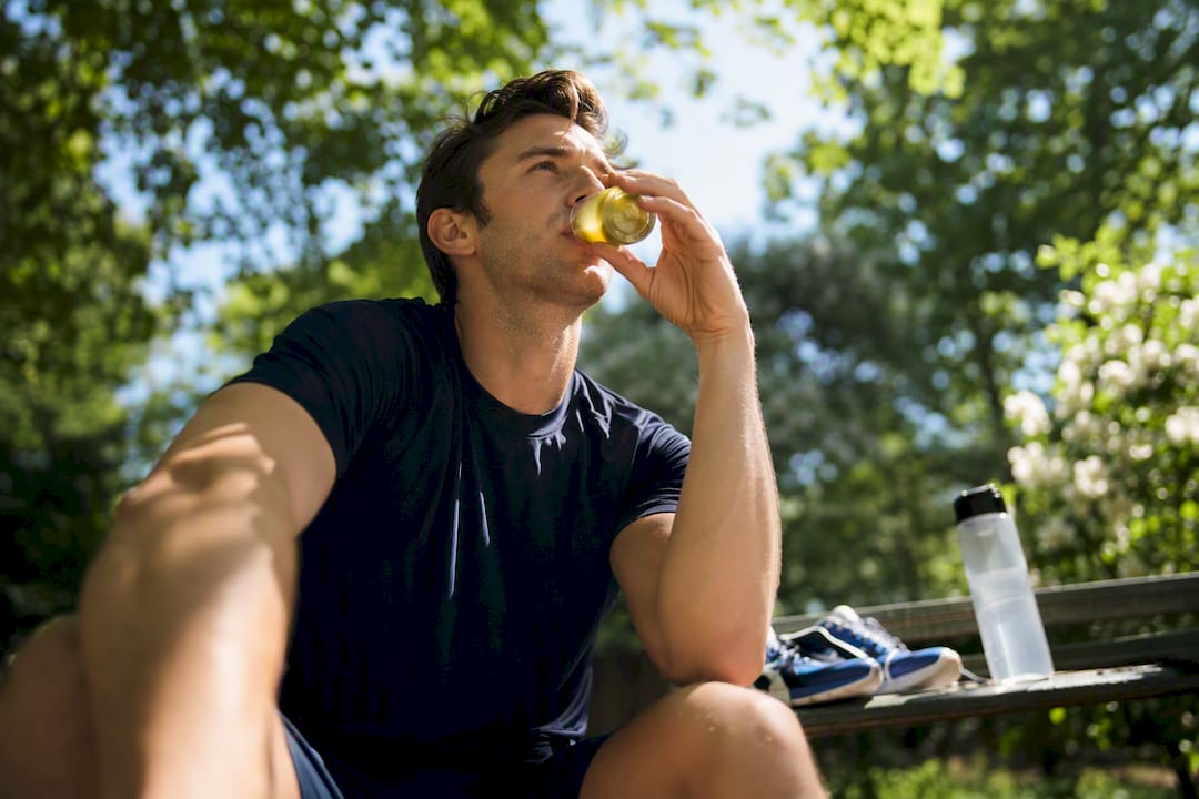 Hardloper die augurkenvocht drinkt buiten