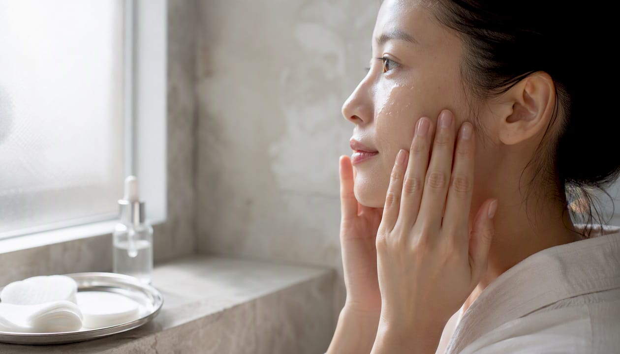 Hands applying serum on face representing niacinamide usage