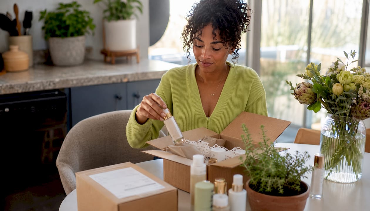Woman packing prepaid return box at home desk