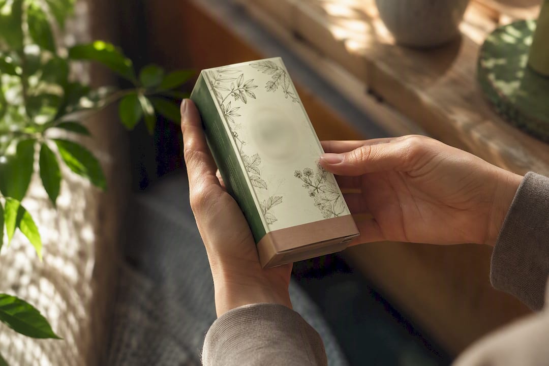 Hands holding green-toned product packaging close-up