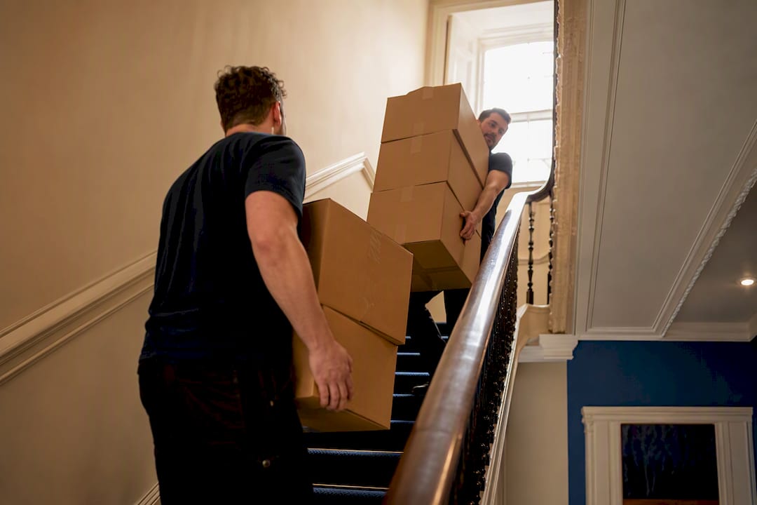 Movers carrying boxes up narrow stairs
