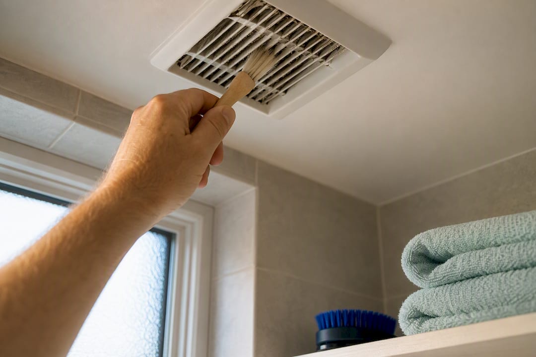 Hand cleaning dust from extractor fan grille