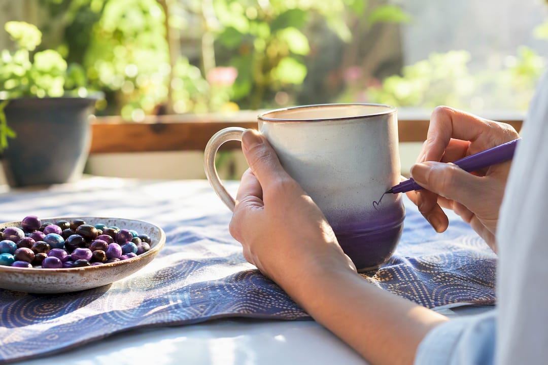 Hands personalizing coffee mug with name