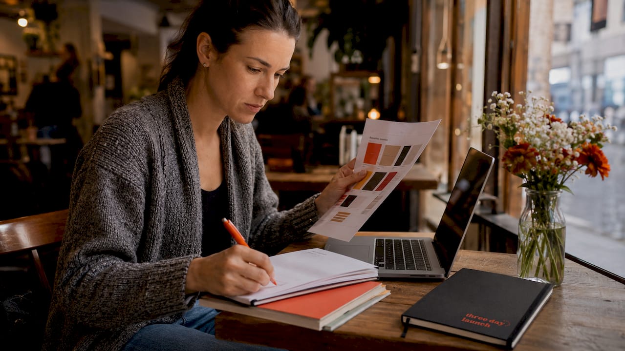 Web designer reviewing printed style guide for brand consistency Web designer reviewing printed style guide for brand consistency
