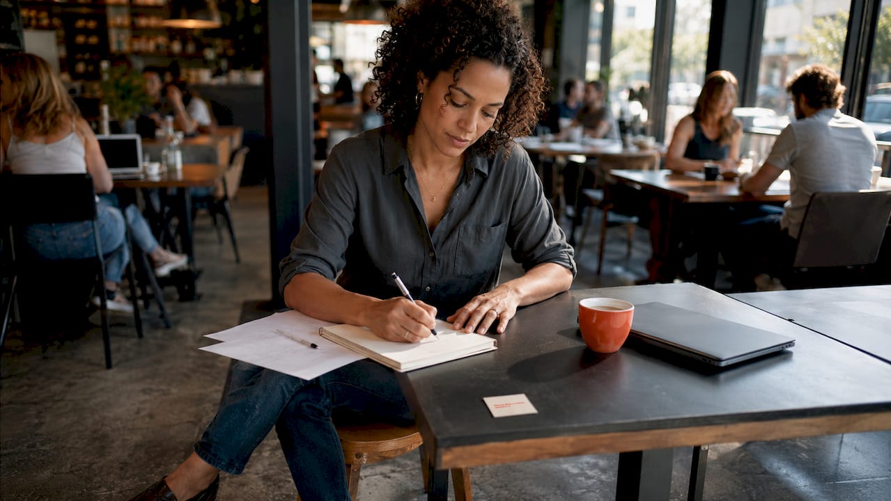 Coach writing sales page notes at desk