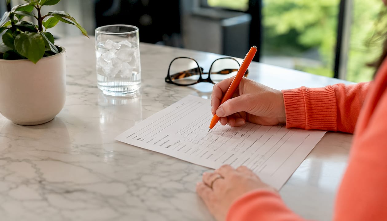 Hands completing coaching intake form with pen