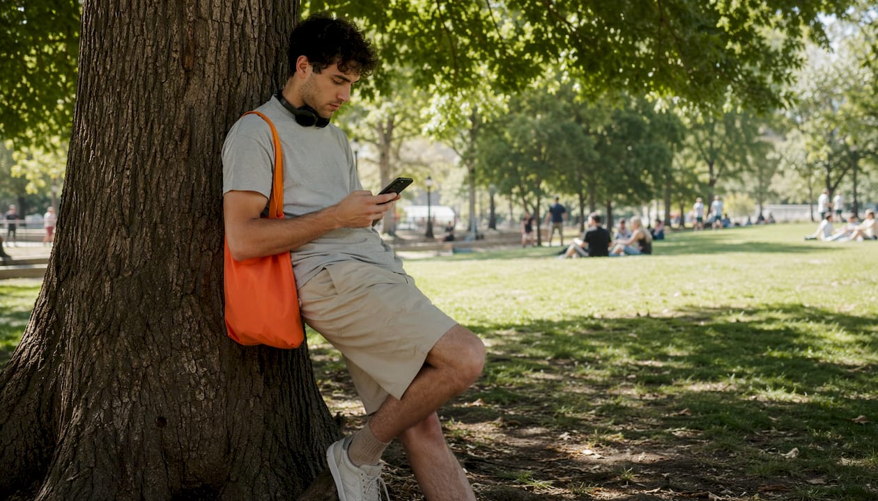 Person using mobile travel app outdoors on park bench