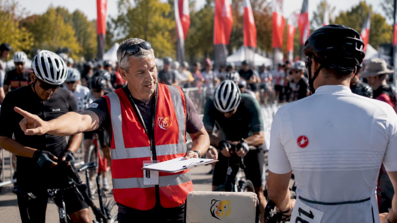 Race volunteer organizing cyclists into corrals