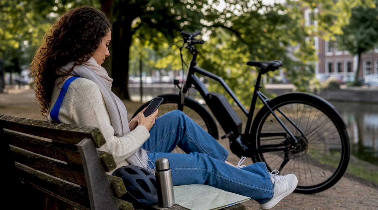 Een vrouw zoekt via haar smartphone de beste route voor haar e-bike.