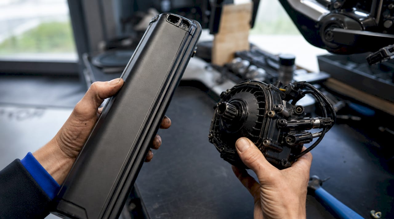 Detailopname van handen die de motor en accu van een e-bike controleren