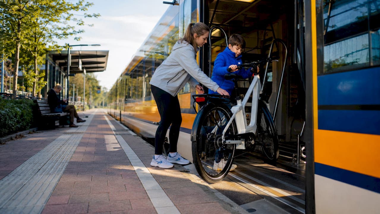 Moeder helpt haar kind om samen de e-bike veilig de trein in te krijgen