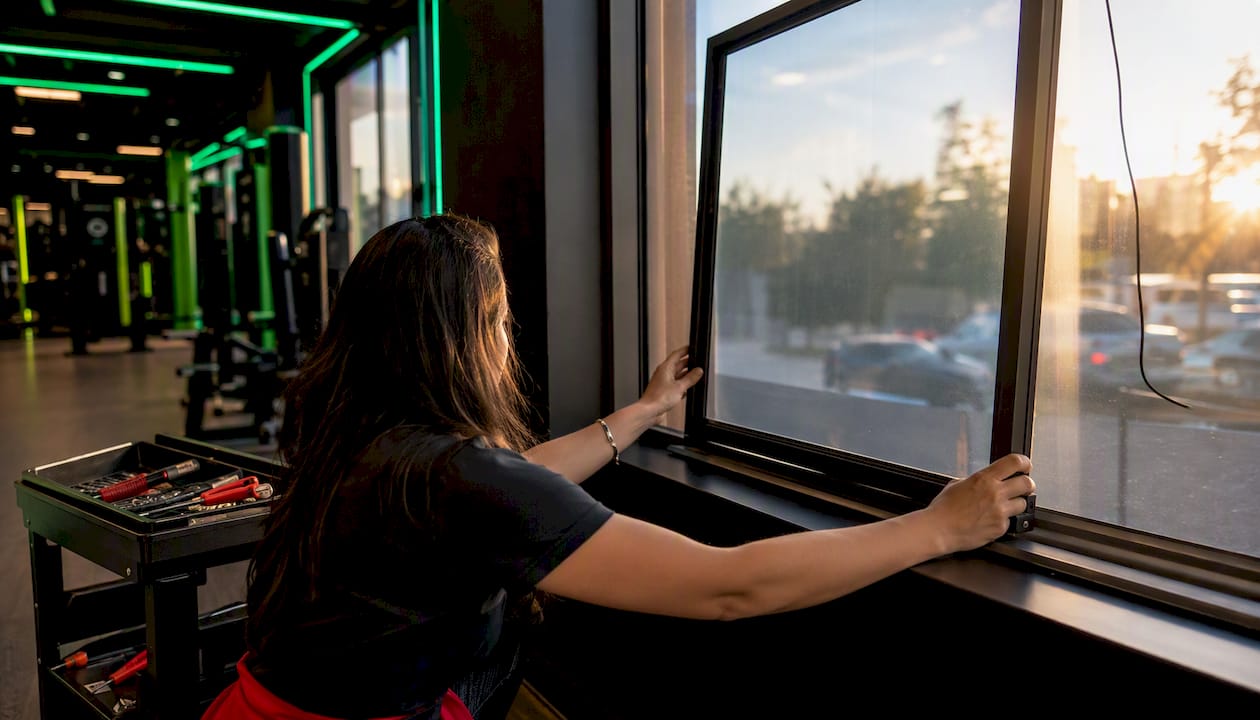 Installer fitting touch frame on gym window display