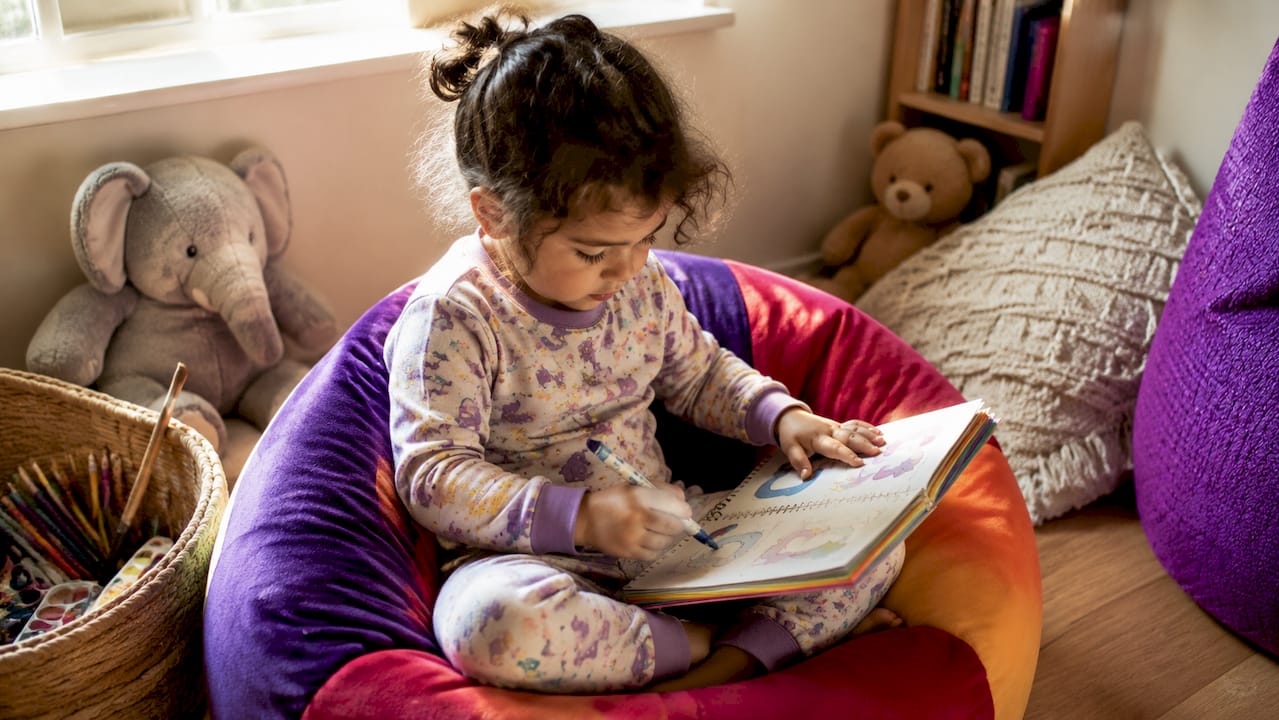 Close-up of child tracing letters on learning book