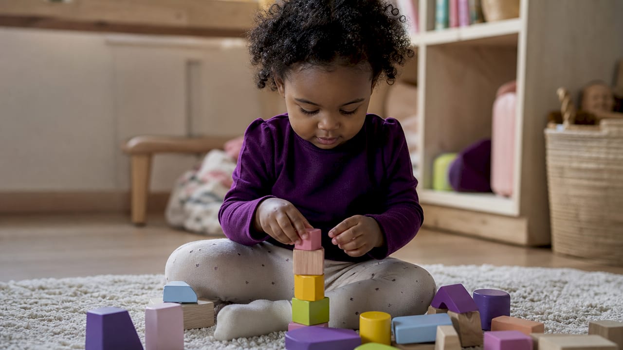 Child shaping playdough letter on table