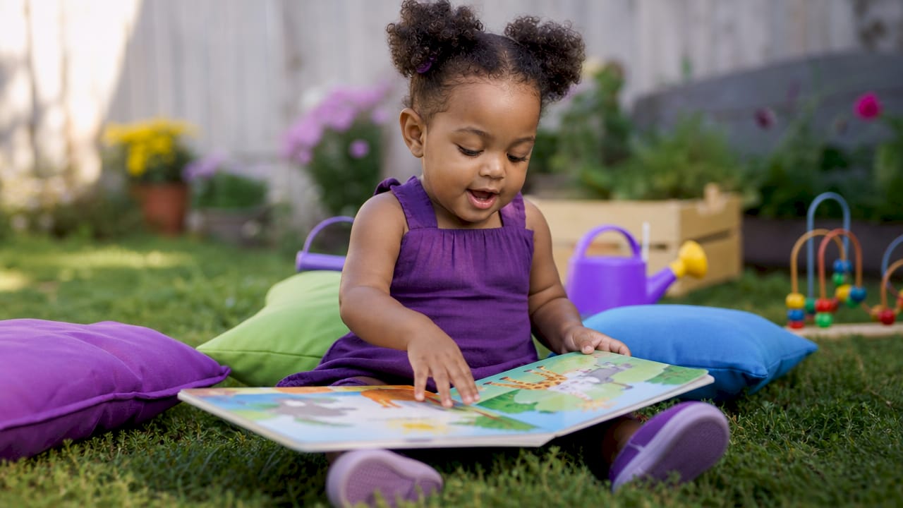 Toddler girl exploring illustrated book at table