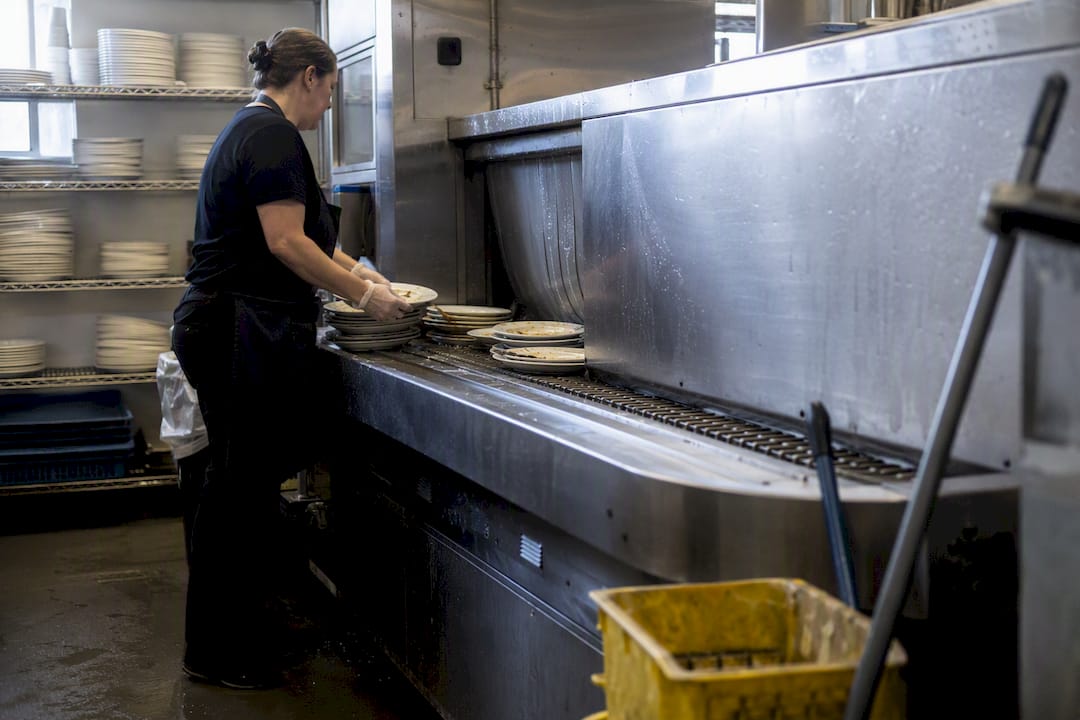 Staff stacking dishes at warewashing station