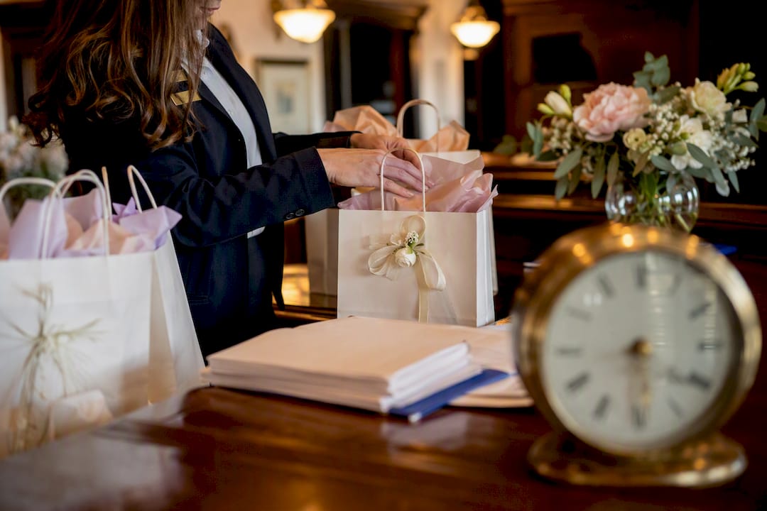 Hands packing wedding welcome bags at hotel desk