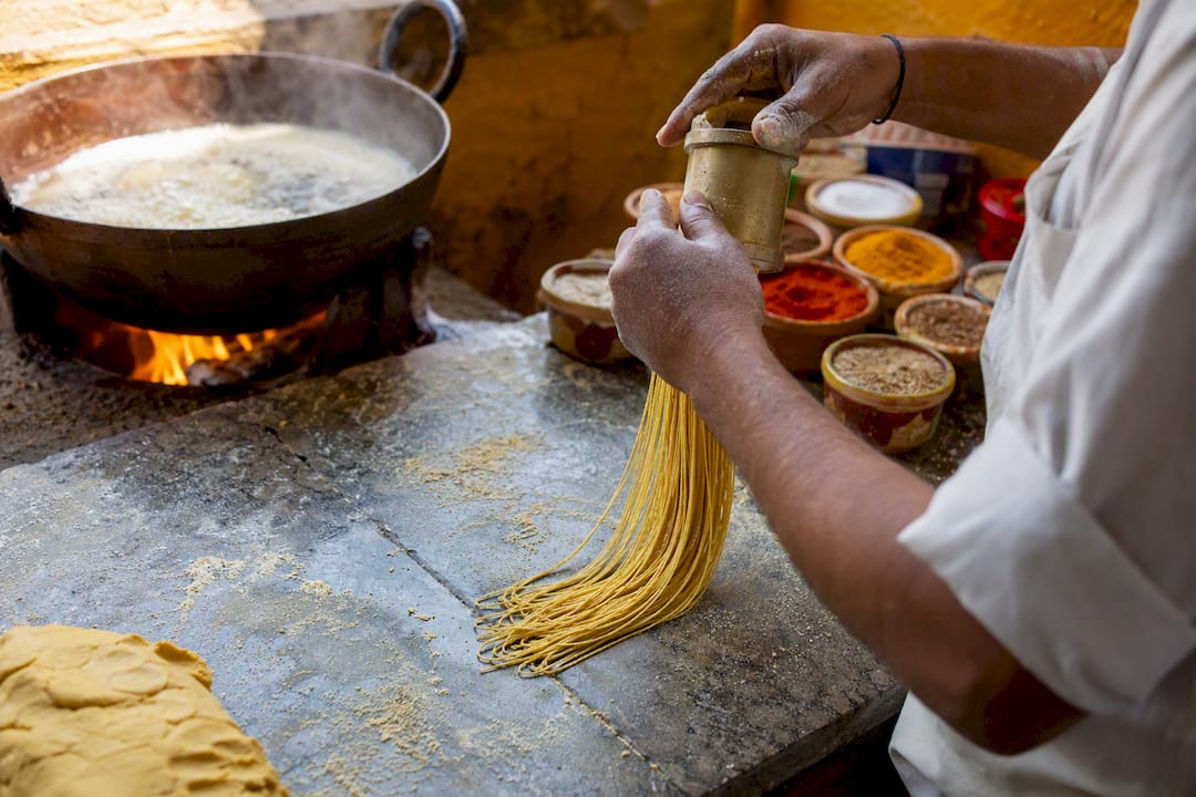 Hands preparing traditional Bikaneri bhujia dough strands