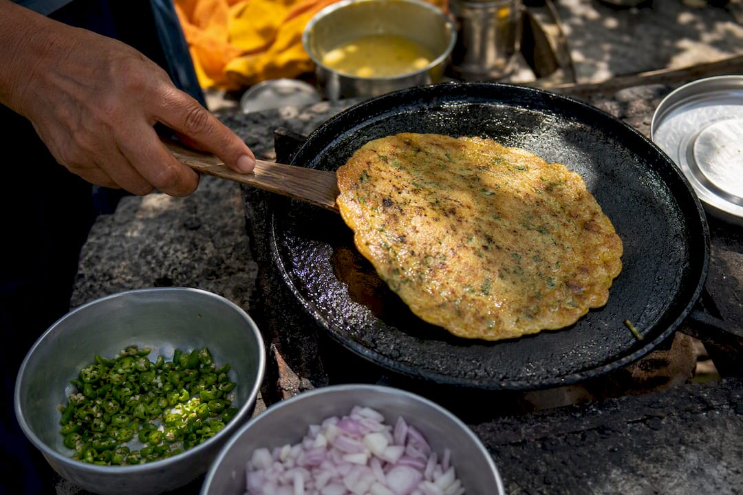 Besan cheela cooking on skillet