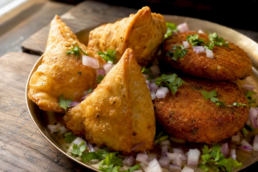 Golden fried samosas and aloo tikkis with spices