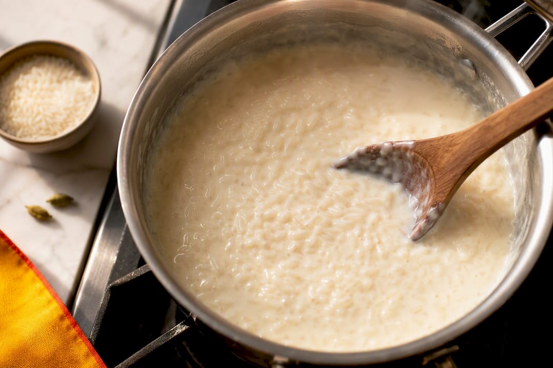Spoon stirring creamy rice kheer in pot