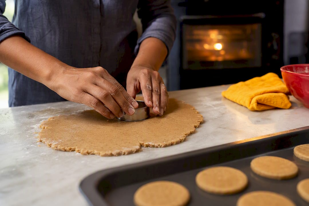 Hands cutting whole-wheat biscuit dough