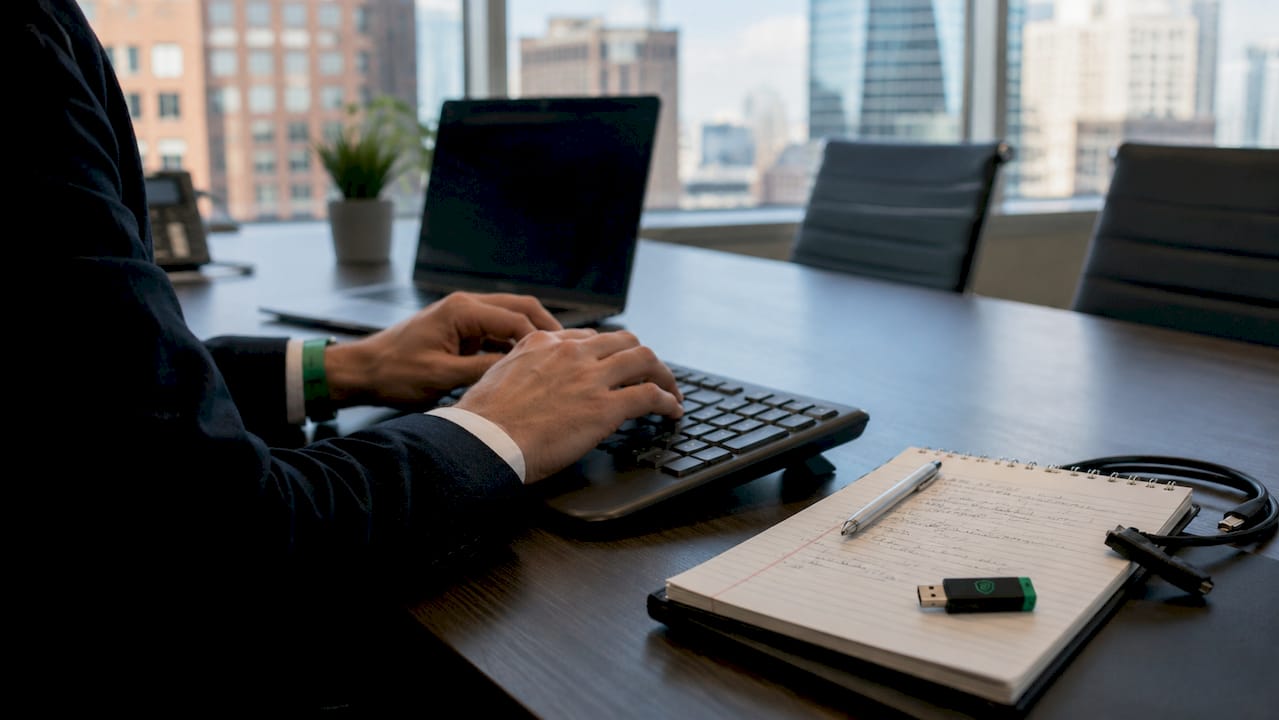 Hands typing security audit notes at IT desk